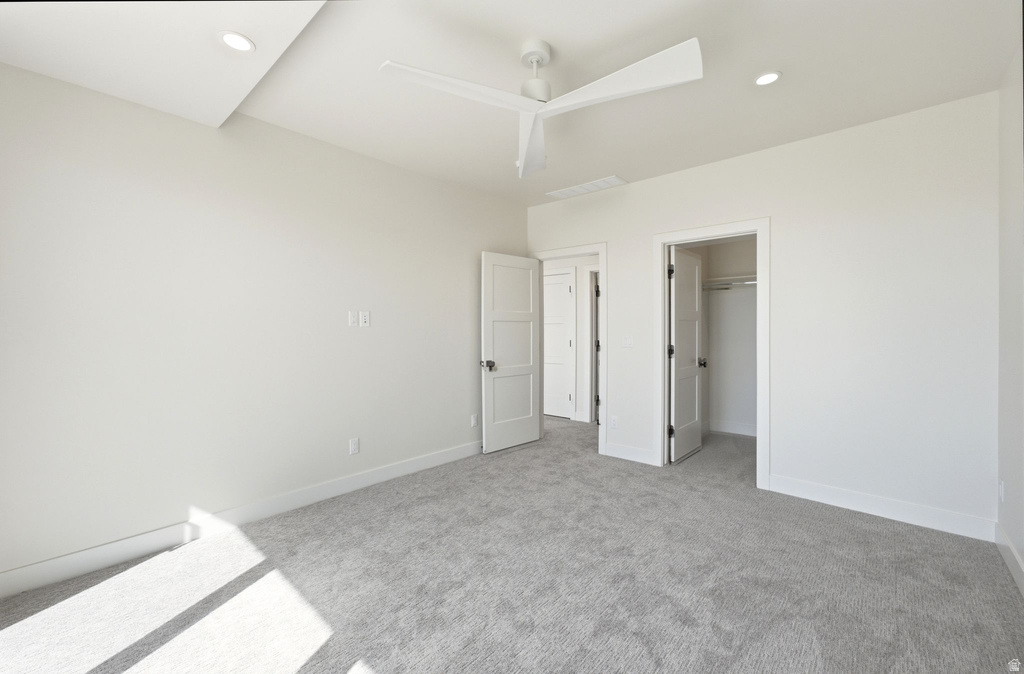 Spacious interior room featuring light gray carpeting, recessed lighting, a modern ceiling fan, and white trim