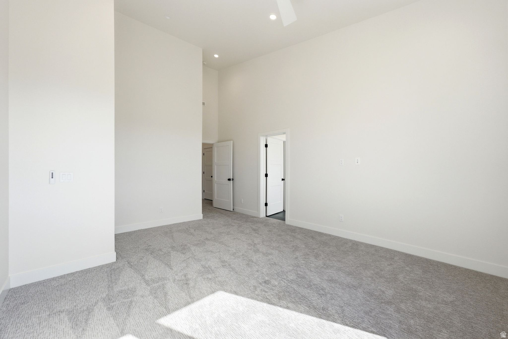 Spacious room featuring vaulted ceilings, light gray carpeting, crisp white walls, and recessed lighting