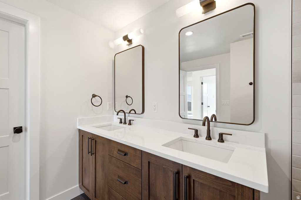 Dual vanity with wood-finish cabinetry, white countertops, and integrated rectangular sinks
