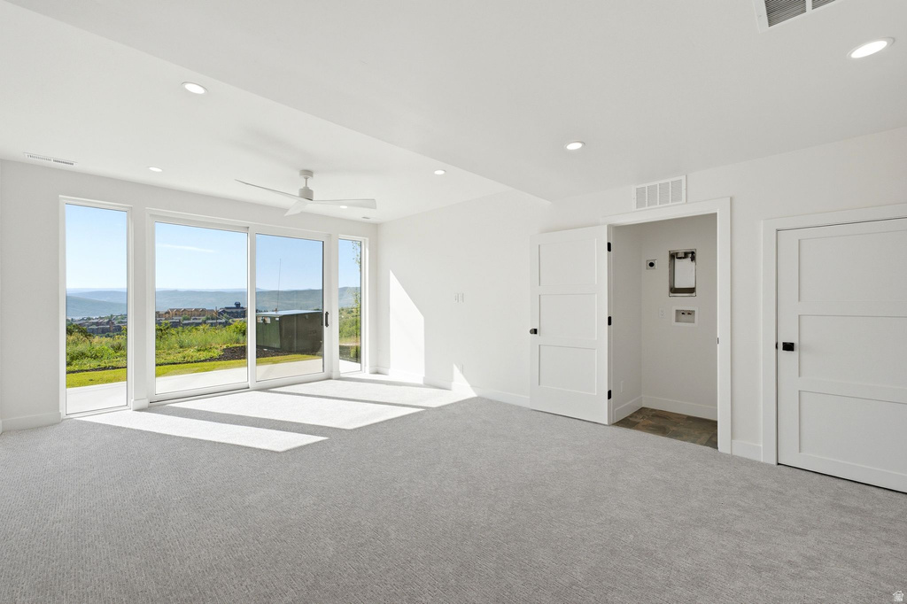 Spacious room with light gray carpeting, recessed lighting, and a ceiling fan
