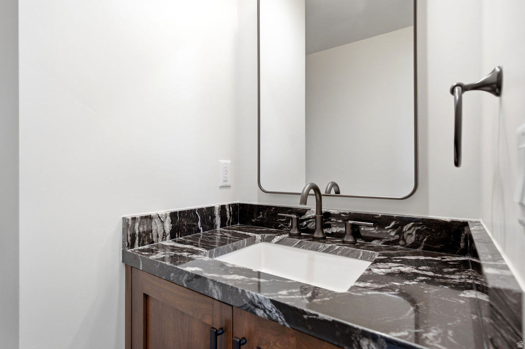 Dark wood-finish vanity with an undermount sink, patterned stone countertop, and dark-toned faucet