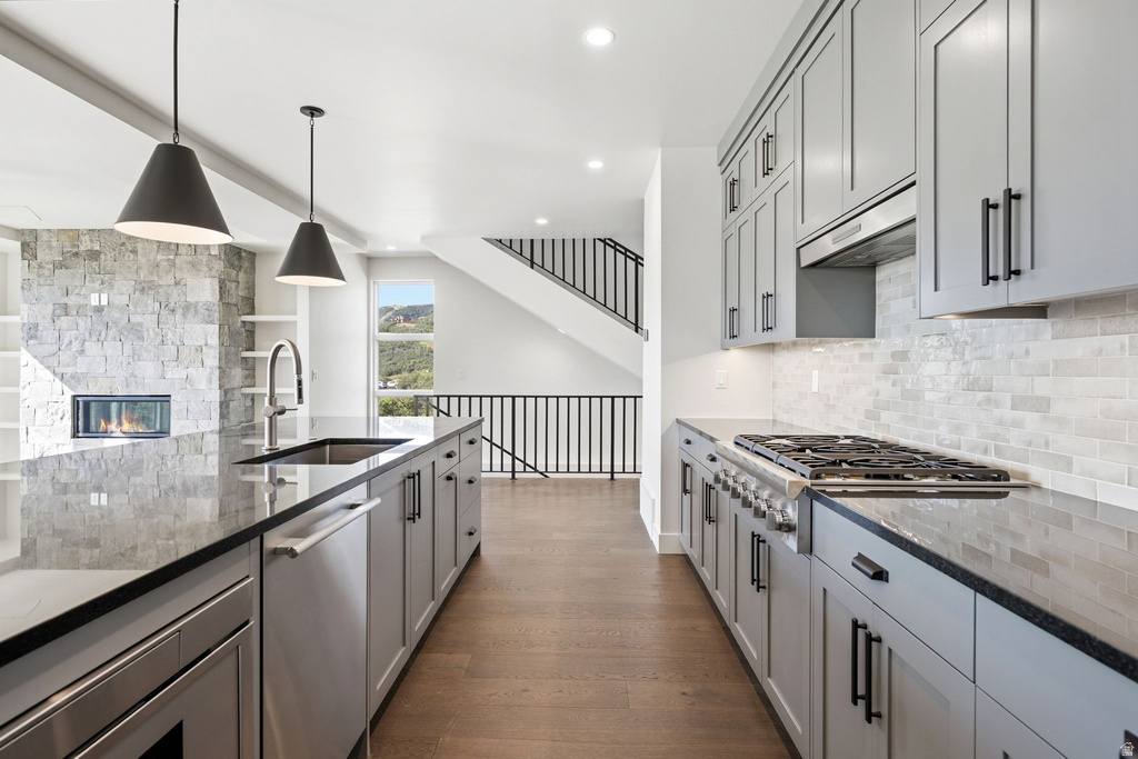 Gourmet kitchen with dark stone countertops, stainless steel appliances, light gray shaker cabinetry, and a subway tile backsplash