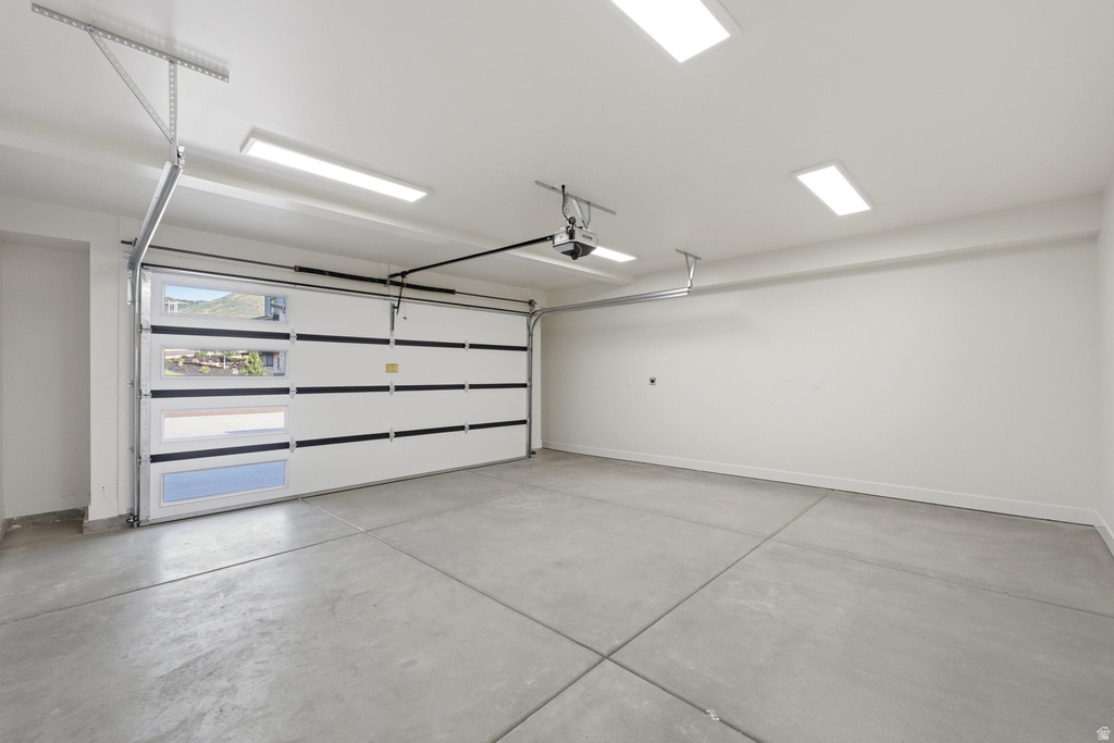 Spacious garage featuring a sectional door with integrated windows, a concrete floor, and bright overhead lighting