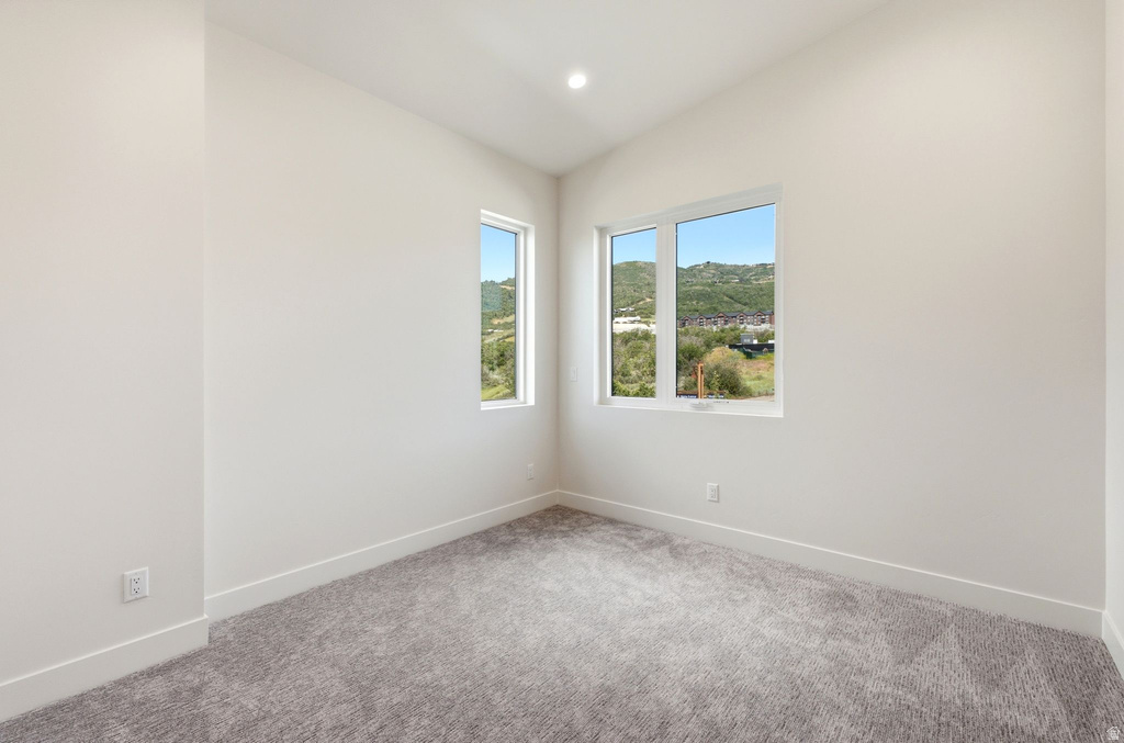 Carpeted room with white walls, two contemporary windows, recessed lighting, and white baseboards