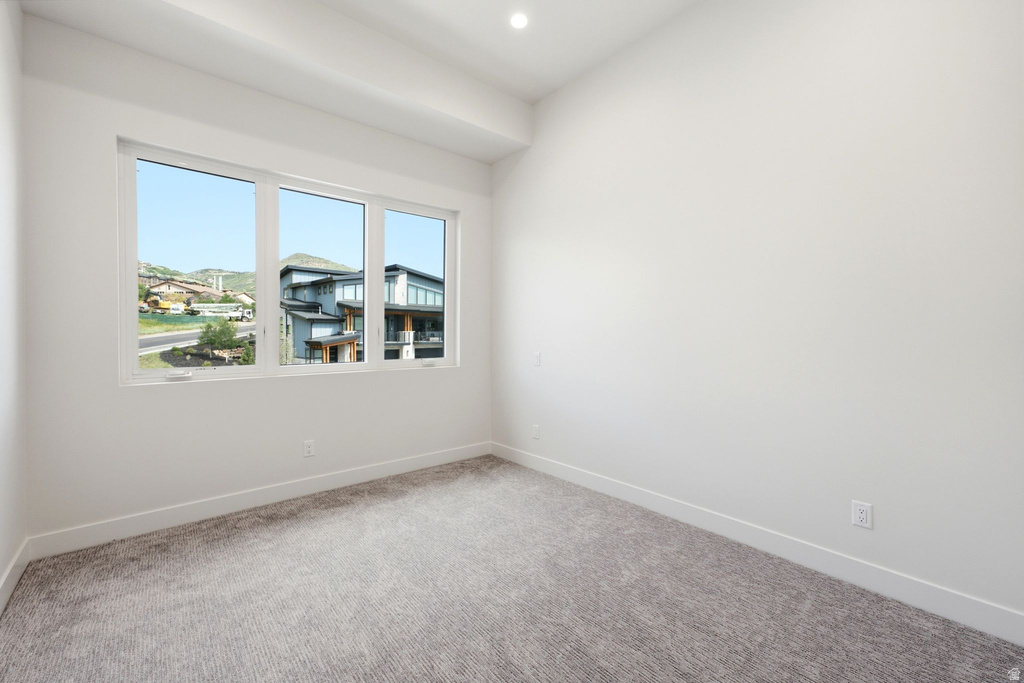 Bright interior space featuring a large three-panel window, light gray carpet, and white baseboards