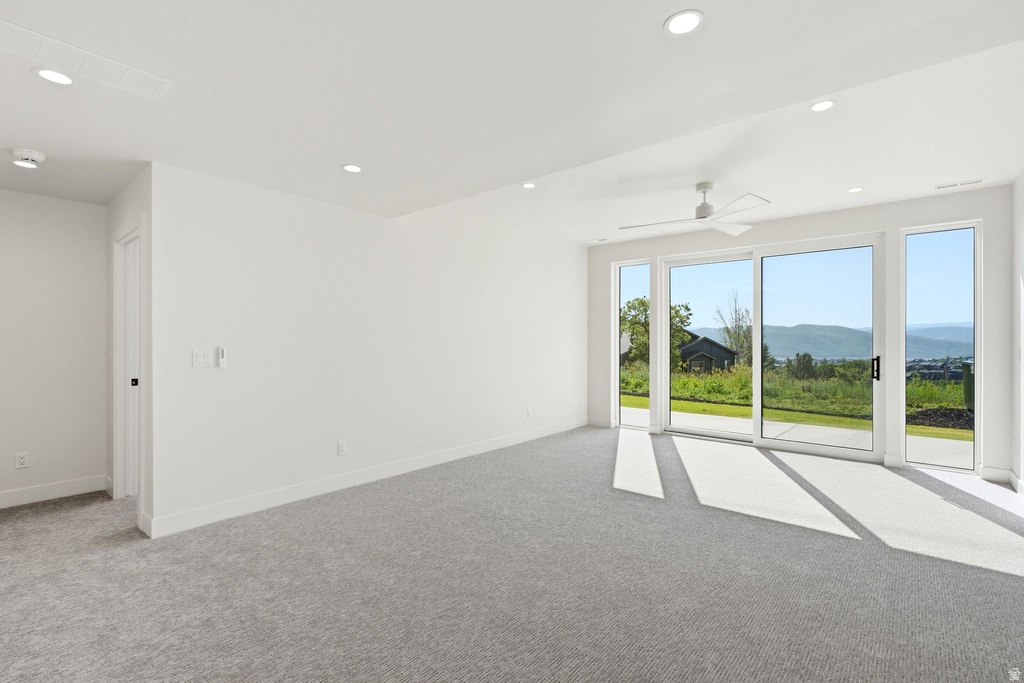 Expansive room featuring a wall of floor-to-ceiling glass panel doors, a contemporary ceiling fan, recessed lighting, and soft grey carpeting