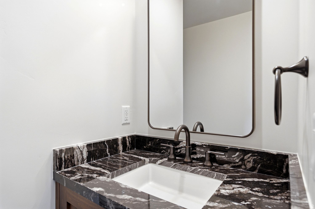 Bathroom vanity featuring a dark stone countertop with white veining, an undermount sink, and dark bronze fixtures