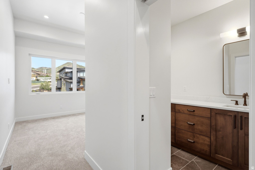 Contemporary vanity with wood-finish cabinetry, white countertop, and rectangular sink