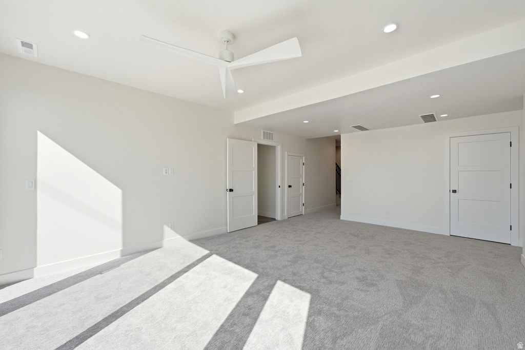 Spacious room featuring light gray carpeting, recessed lighting, a modern ceiling fan, three-panel interior doors, and white baseboards