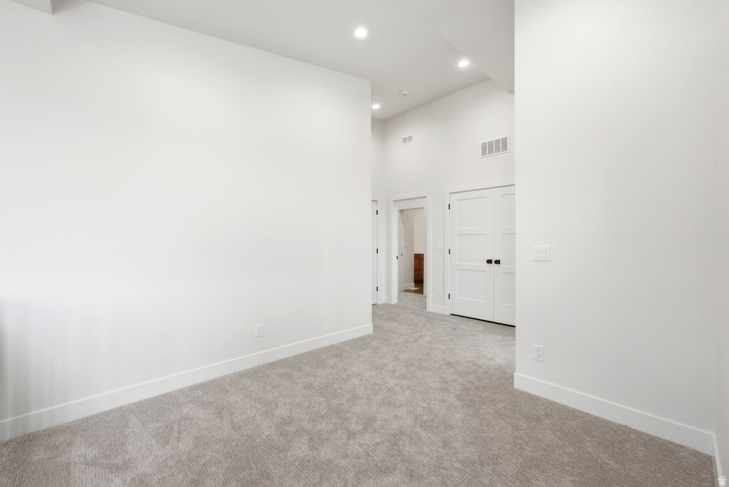 Carpeted interior with high ceilings, recessed lighting, white walls, and white trim