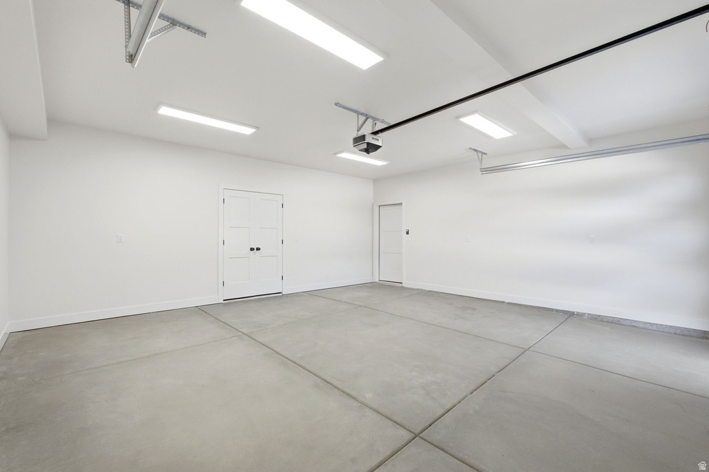 Spacious garage featuring a concrete floor, bright overhead lighting, and white painted walls