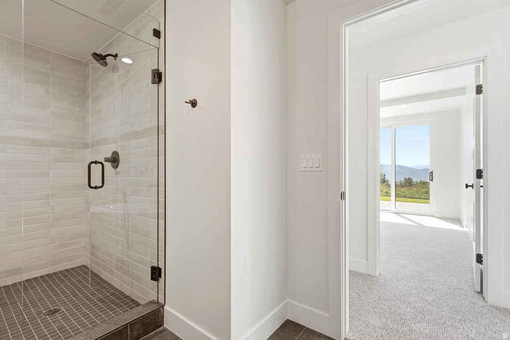 Tiled shower with a clear glass enclosure and dark bronze fixtures
