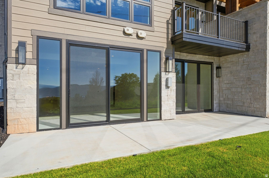 Spacious concrete patio with sliding glass doors, stone facade accents, and horizontal siding