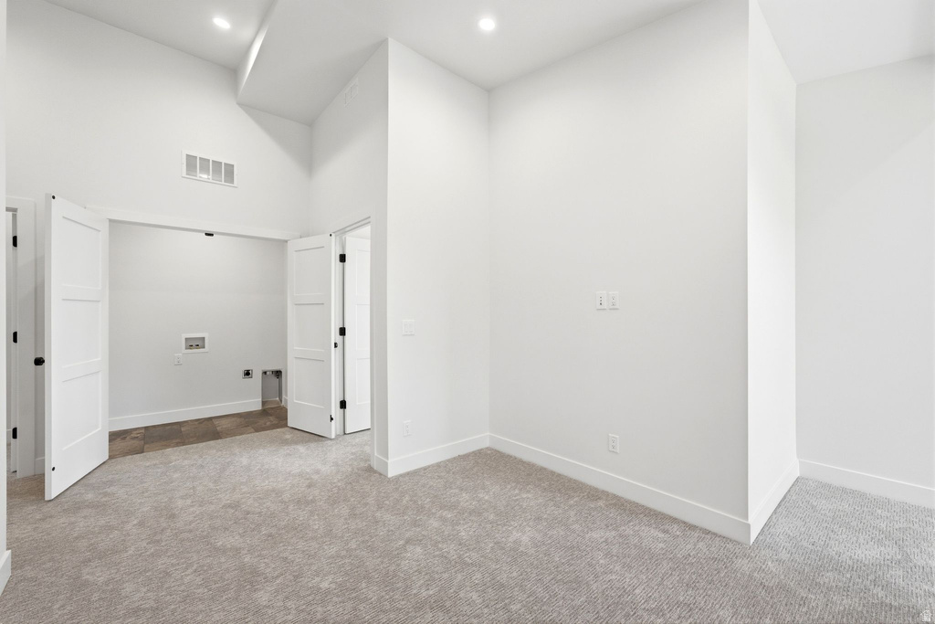 Spacious interior room featuring light gray carpet flooring and white walls