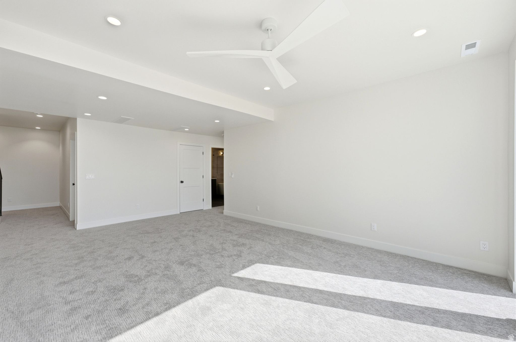 Spacious room featuring light gray carpeting, recessed lighting, a modern ceiling fan, white baseboards, and a white interior door with black hardware