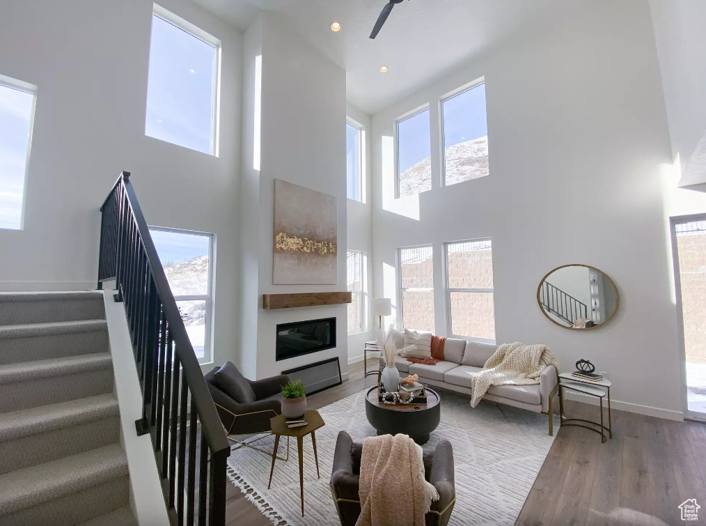 Living room with wood finished floors, a glass covered fireplace, recessed lighting, stairway, and baseboards