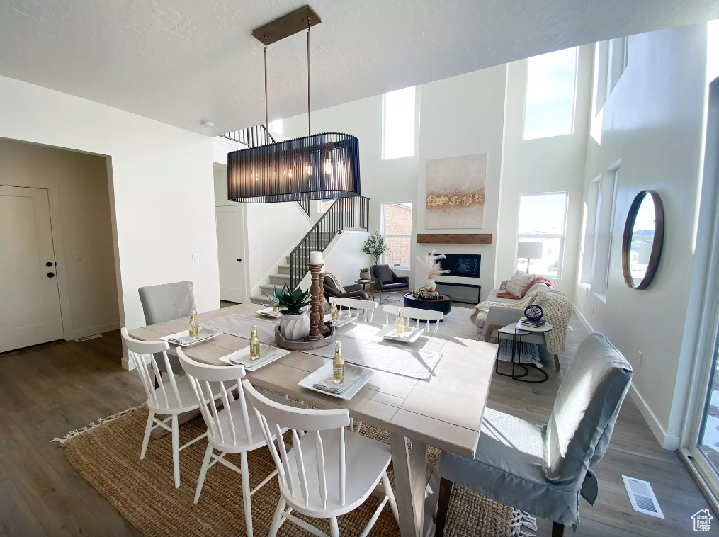 Dining space with a glass covered fireplace, stairway, baseboards, and wood finished floors