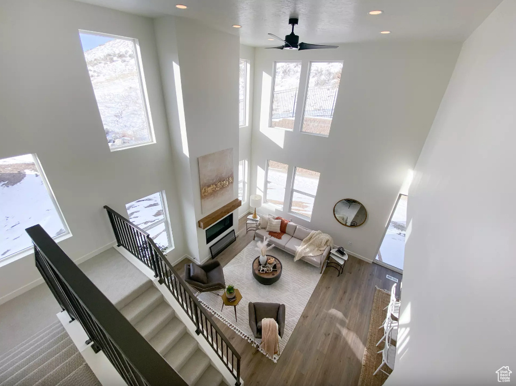 Living area featuring stairway, wood finished floors, baseboards, recessed lighting, and a towering ceiling