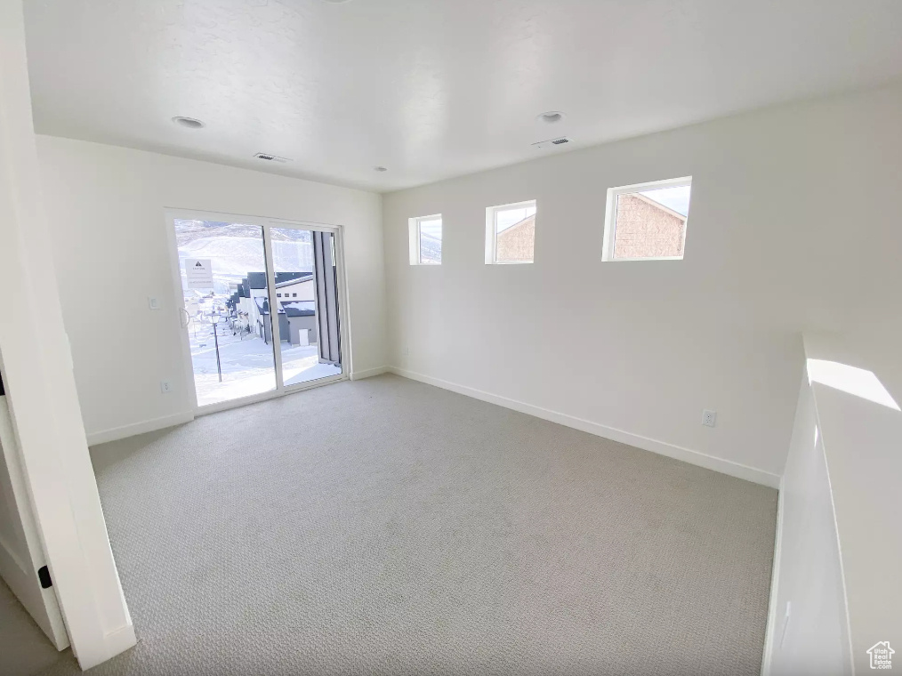 Carpeted empty room with visible vents and baseboards