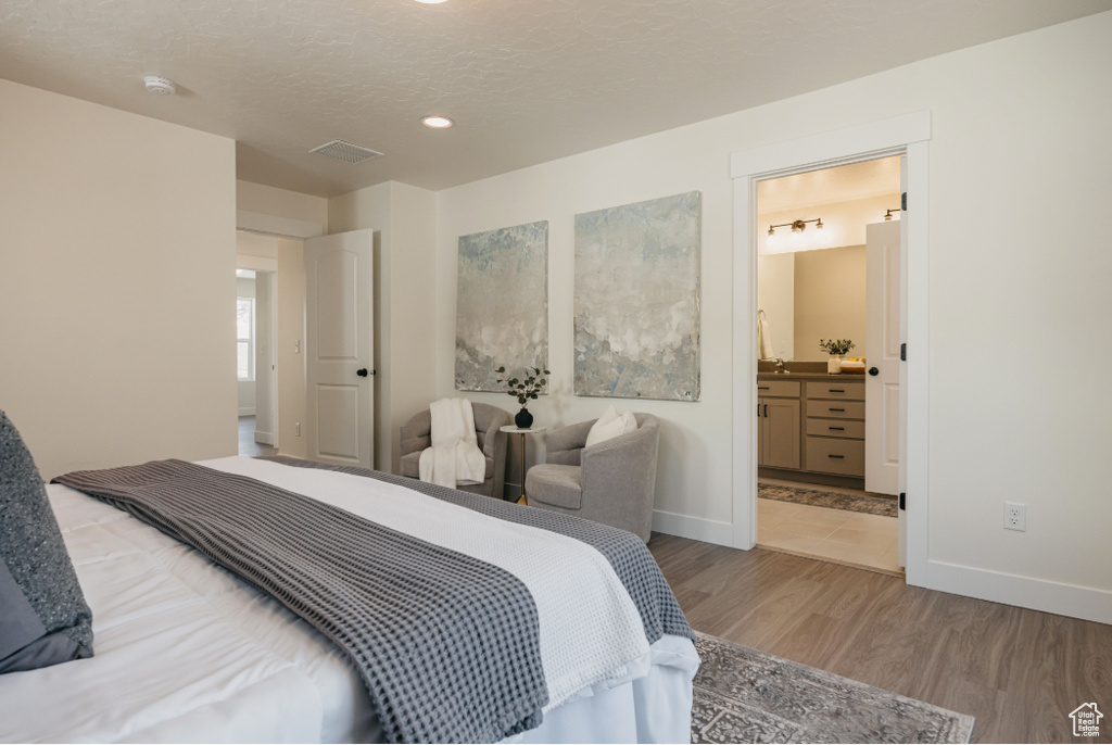 Bedroom featuring visible vents, a textured ceiling, baseboards, and wood finished floors
