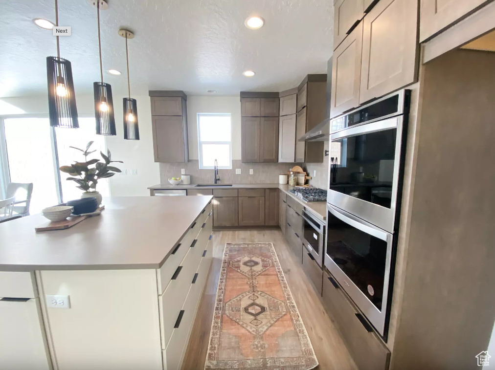 Kitchen with light countertops, tasteful backsplash, stainless steel appliances, and a sink