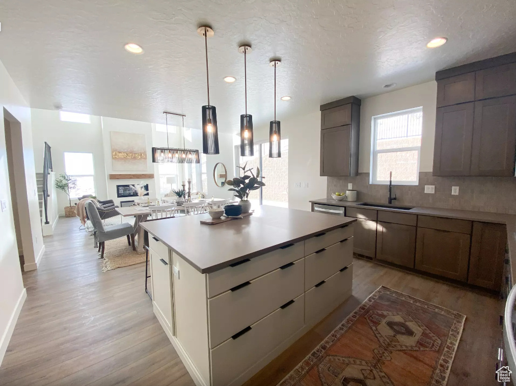 Kitchen featuring light wood finished floors, backsplash, a center island, and a sink