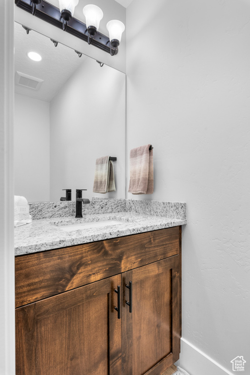 Bathroom featuring visible vents, vanity, and baseboards