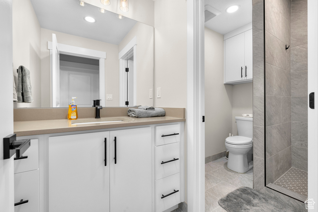 Bathroom with vanity, recessed lighting, a tile shower, tile patterned floors, and toilet