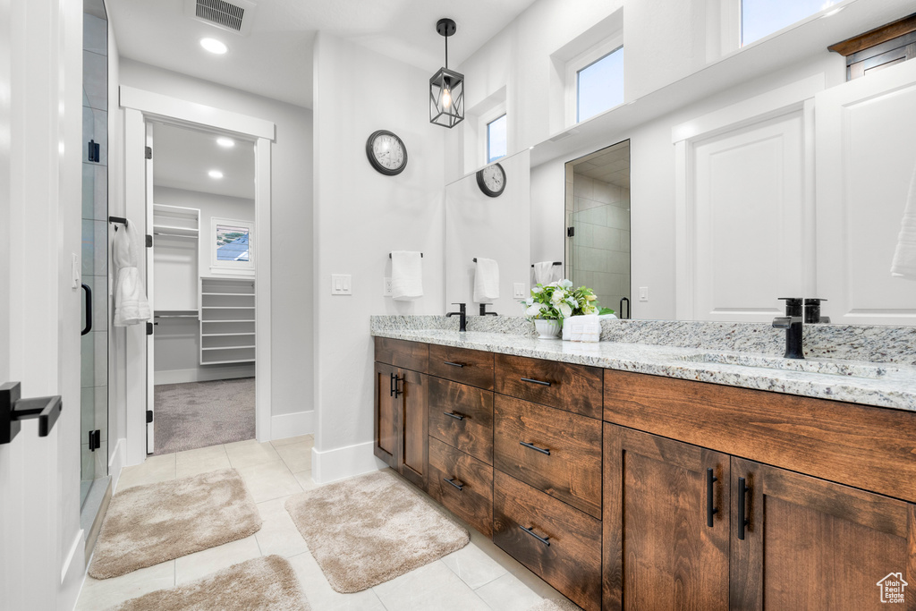 Bathroom with visible vents, double vanity, a sink, a shower stall, and a walk in closet