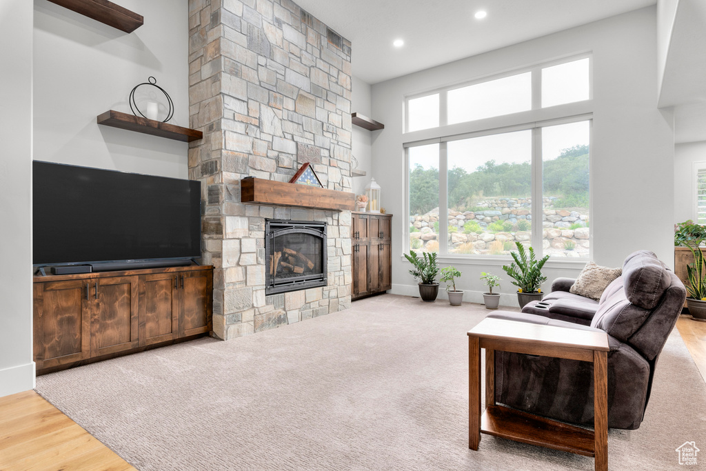 Living room with a stone fireplace, a high ceiling, recessed lighting, and baseboards