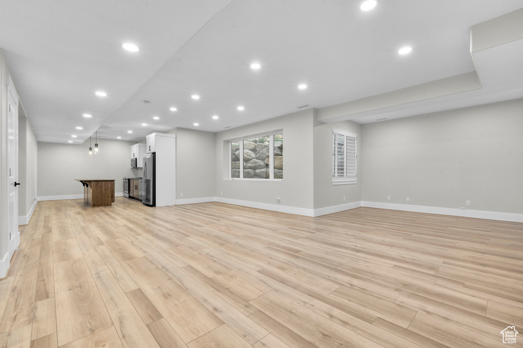 Unfurnished living room with recessed lighting, baseboards, and light wood-style flooring