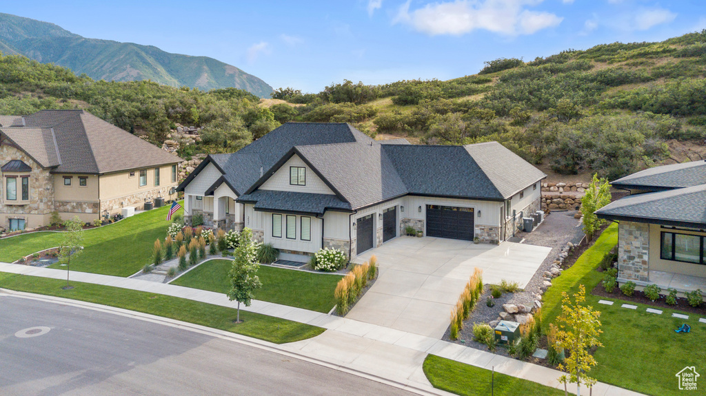 View of front of home featuring roof with shingles, an attached garage, concrete driveway, stone siding, and a mountain view