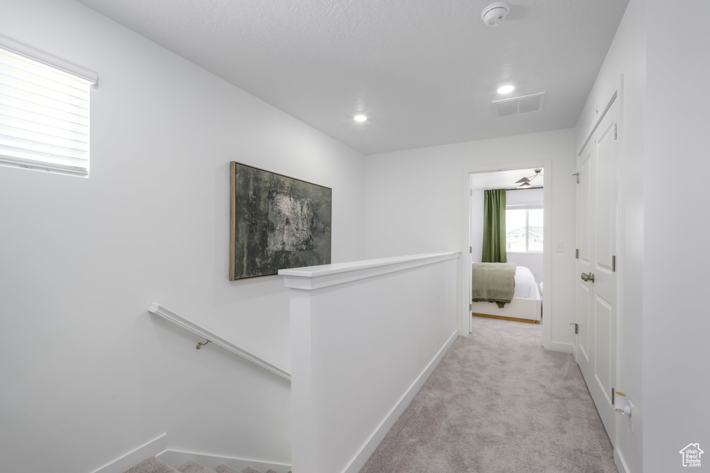 Hall with baseboards, visible vents, an upstairs landing, and carpet floors