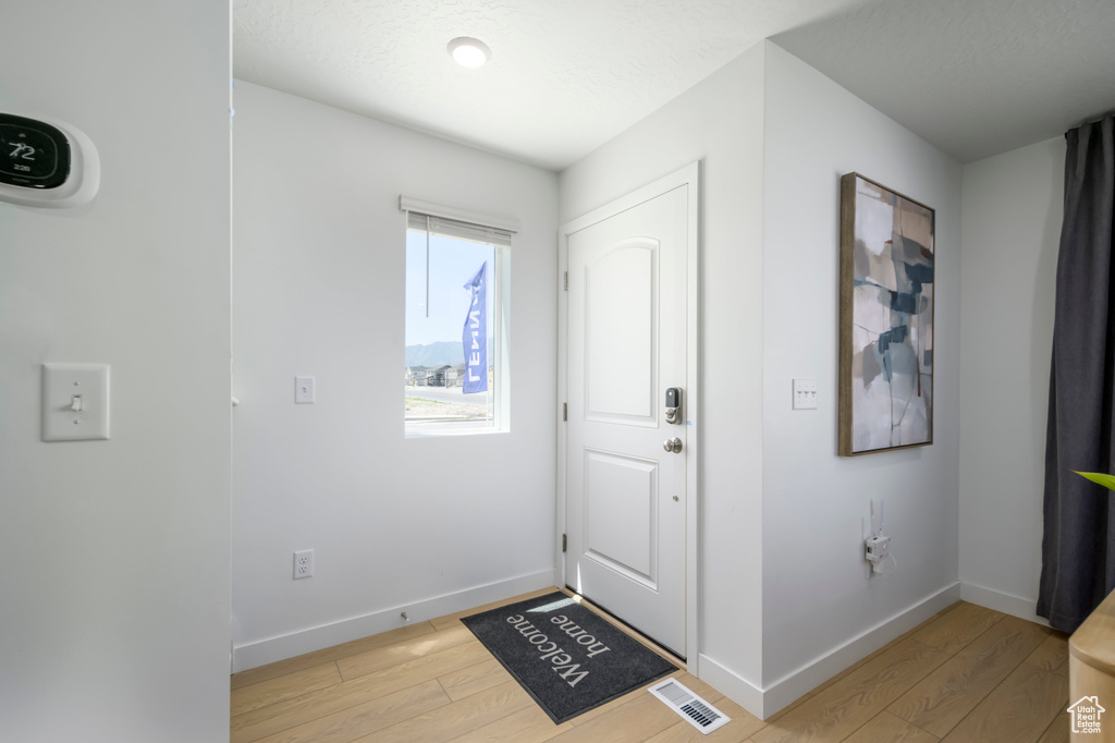 Entryway with baseboards, visible vents, and light wood finished floors