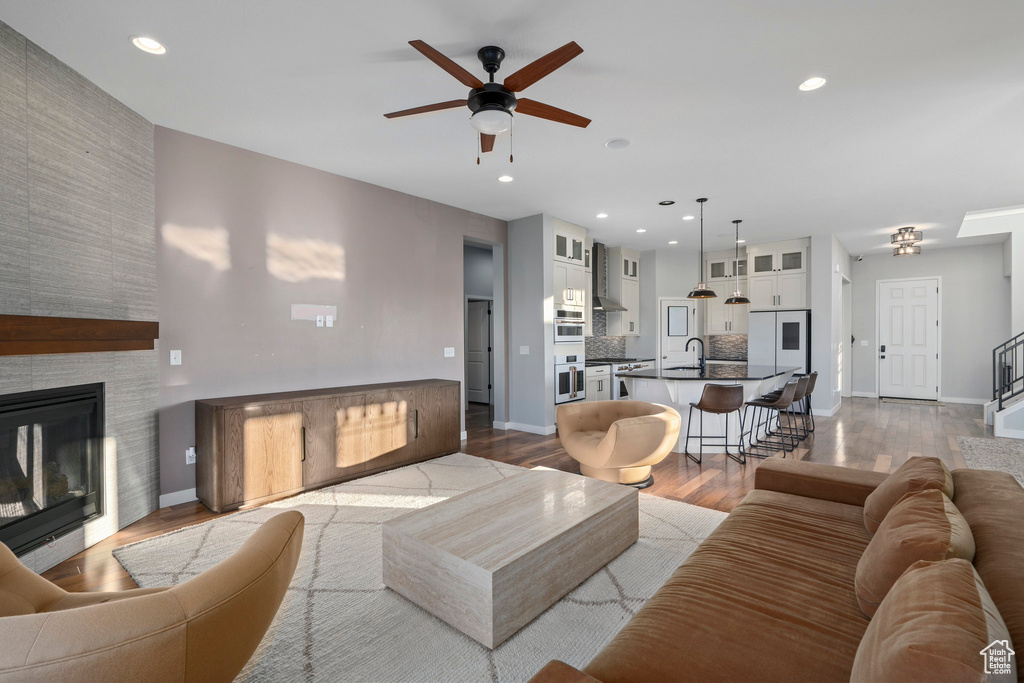 Living room featuring recessed lighting, a fireplace, dark wood-style flooring, and baseboards