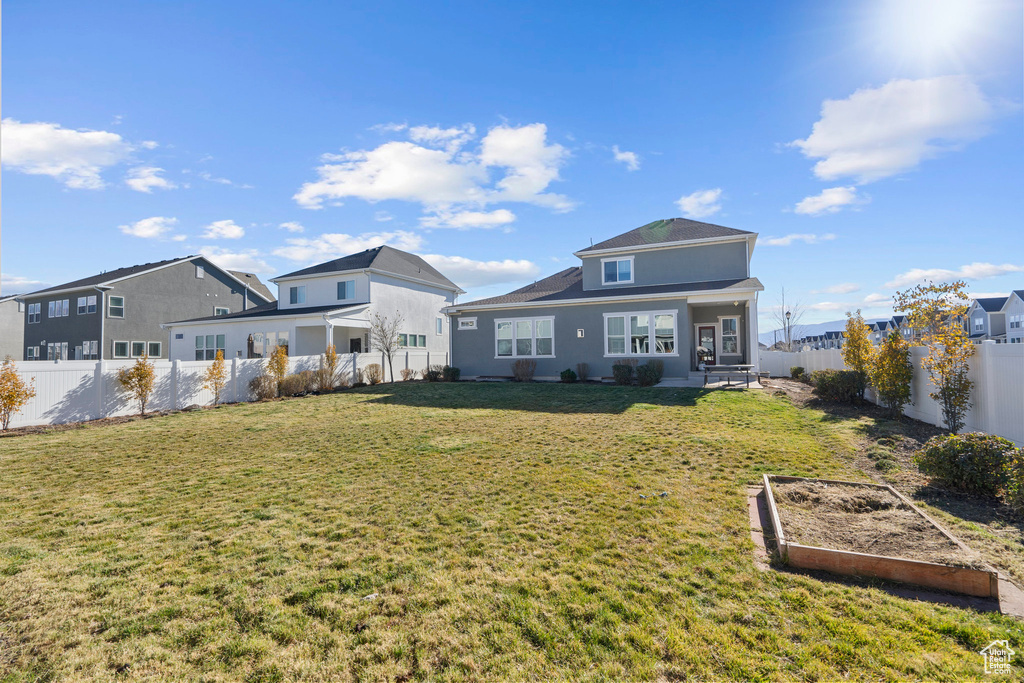 Back of house with a garden, a lawn, and a fenced backyard