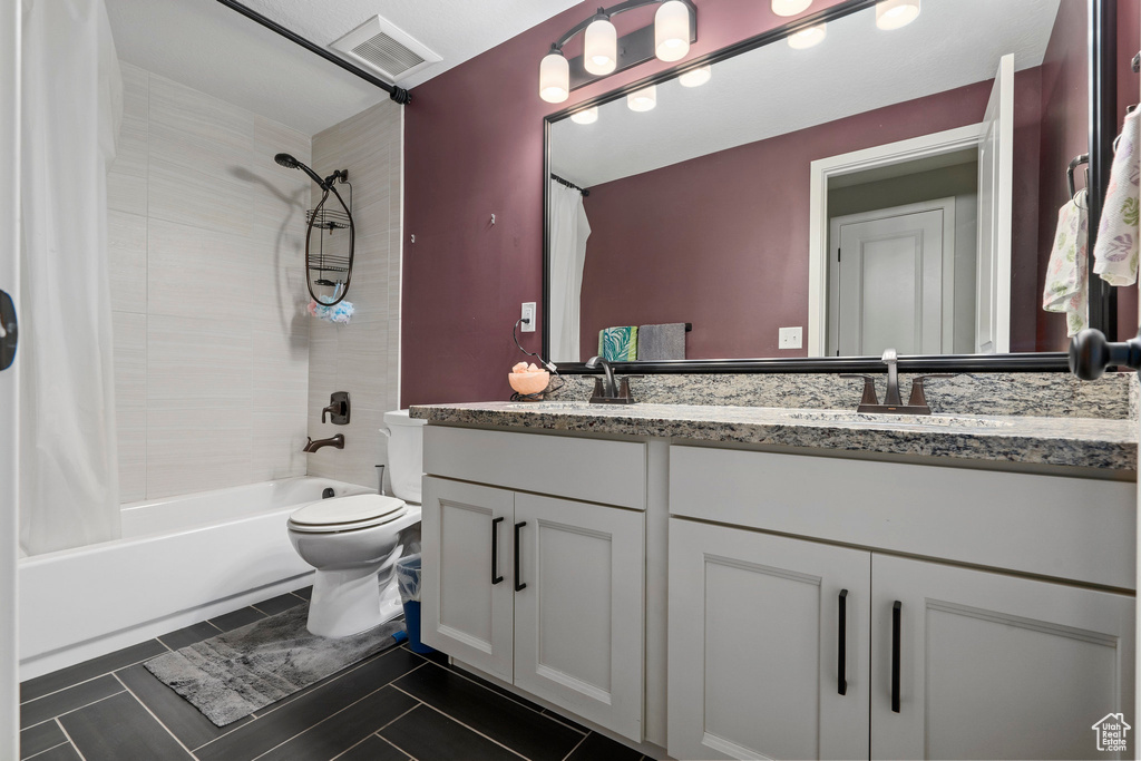 Bathroom with visible vents, shower / bathtub combination with curtain, toilet, a sink, and double vanity