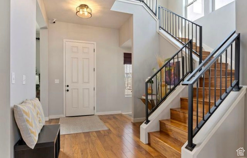 Foyer entrance featuring wood finished floors, baseboards, and a towering ceiling