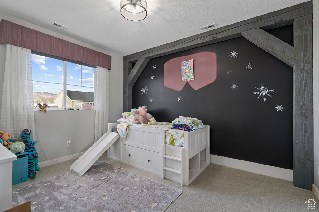 Carpeted bedroom featuring visible vents, baseboards, and an accent wall