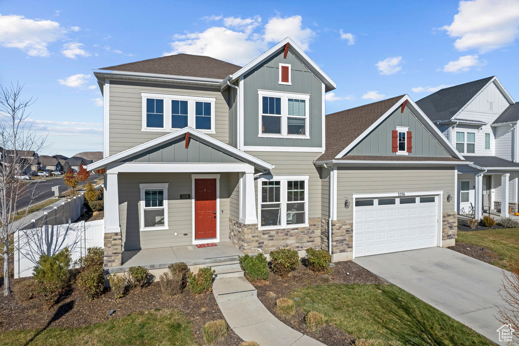 Craftsman inspired home featuring board and batten siding, fence, a porch, stone siding, and driveway