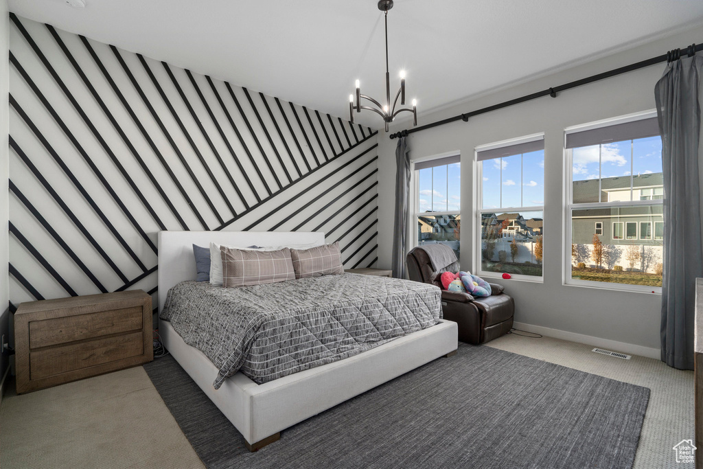 Carpeted bedroom with visible vents, an inviting chandelier, wallpapered walls, baseboards, and an accent wall