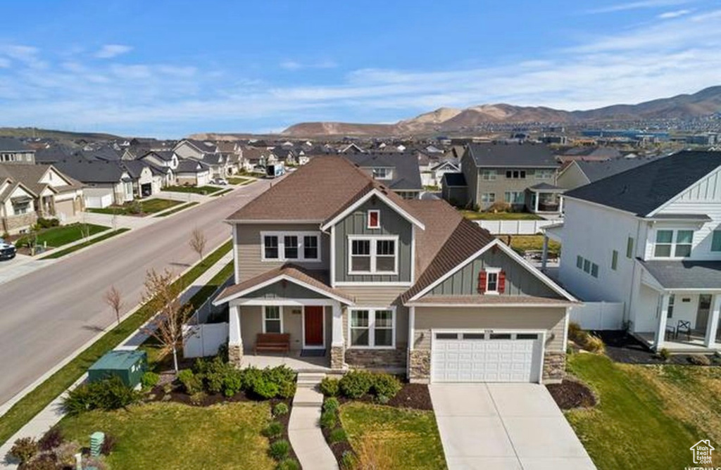 View of front of house featuring a mountain view, a residential view, concrete driveway, stone siding, and board and batten siding