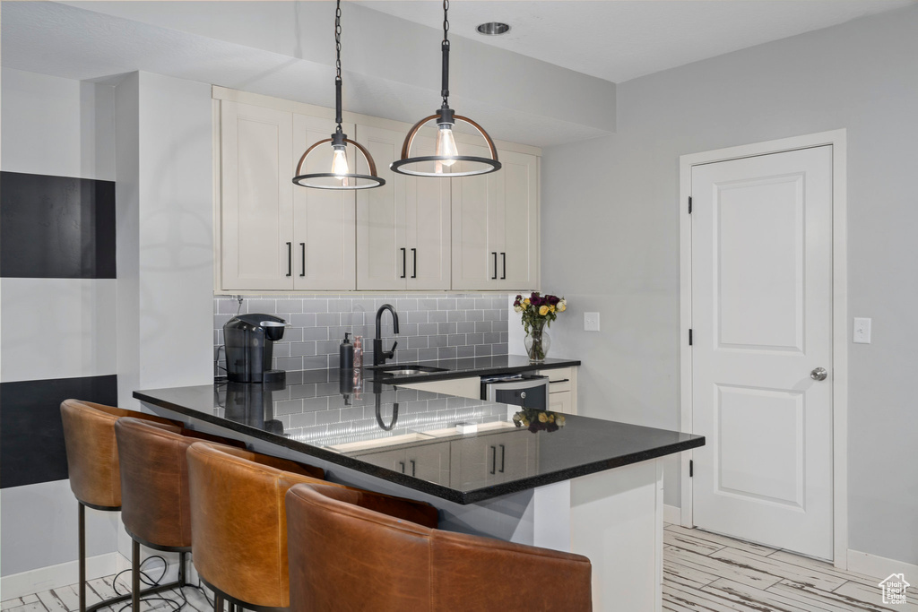 Kitchen featuring tasteful backsplash, dishwashing machine, white cabinets, and a sink