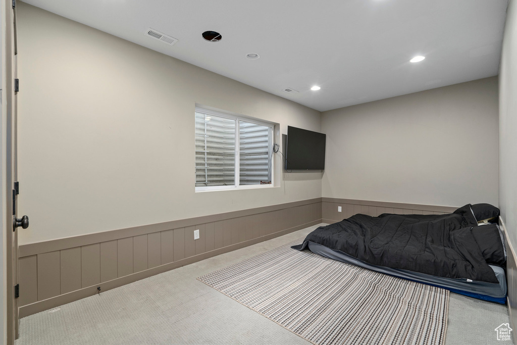 Carpeted bedroom featuring a wainscoted wall, recessed lighting, and visible vents