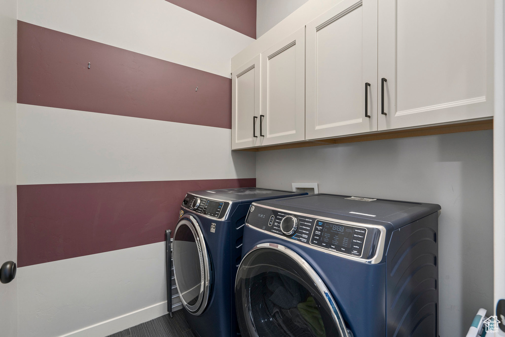 Laundry room featuring washing machine and clothes dryer, cabinet space, and baseboards