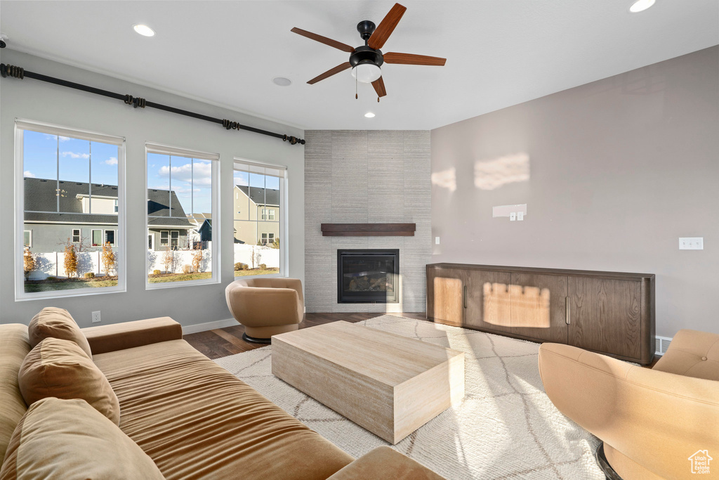 Living room with wood finished floors, recessed lighting, a fireplace, baseboards, and ceiling fan
