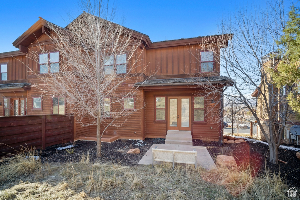 View of front facade featuring french doors, fence, and board and batten siding