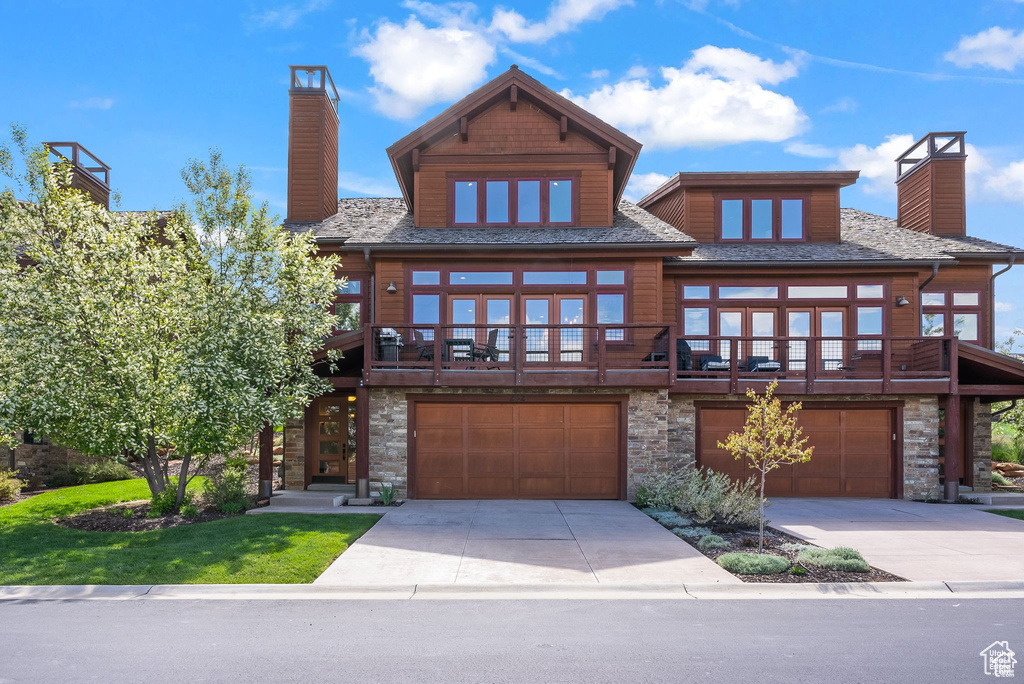 View of front of house with a chimney, an attached garage, stone siding, and concrete driveway