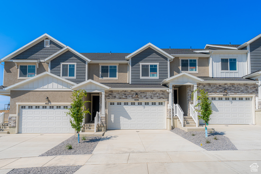 Multi unit property with board and batten siding, a garage, concrete driveway, and stone siding