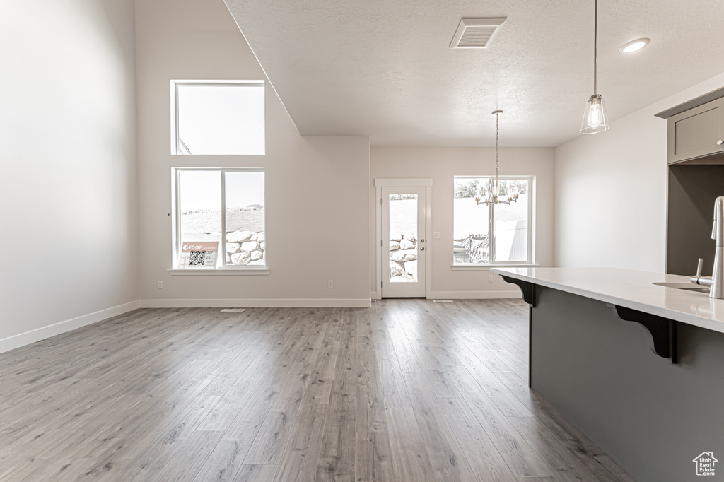 Kitchen with a breakfast bar, healthy amount of natural light, light wood-style floors, a chandelier, and a textured ceiling